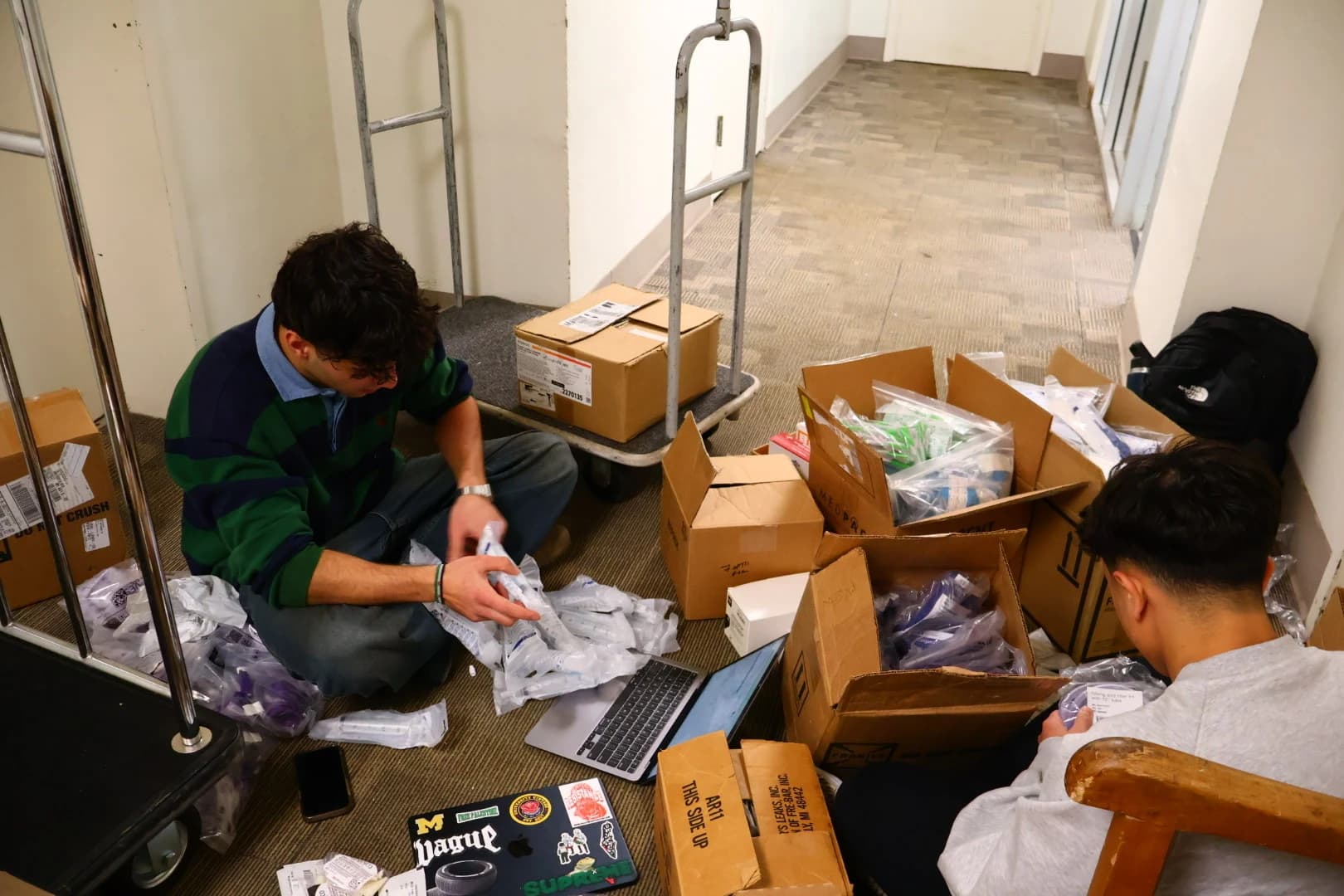 Project Resurge volunteers organizing medical supplies beside boxes and a delivery cart